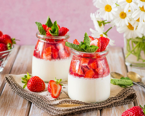 Zwei Gläser gefüllt mit frischen Erdbeeren und cremigem Quark